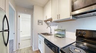 This well-organized one-bedroom, one-bathroom unit offers a thoughtful layout across a single floor, making efficient use of every square foot. The open living area is anchored by warm wood-look flooring that flows throughout the space, neutral white walls, and a paneled ceiling that adds subtle texture. A window fitted with horizontal blinds brings in natural light and overlooks the outdoors, while a baseboard heating system ensures year-round comfort.

The kitchen is efficiently designed with white shaker-style cabinetry, gray quartz-style countertops, and a white subway tile backsplash. It is equipped with stainless steel appliances including an electric range, over-the-range microwave, and dishwasher, along with a stainless undermount sink — providing a clean, functional cooking space.

The bedroom is a calm, minimal retreat featuring the same wood-look flooring, crisp white walls, and a window with blinds that allows for natural light and ventilation. A baseboard heater lines the wall, ensuring the room stays comfortable.

The bathroom features a full soaking tub with a shower surround, a white vanity with gray countertop and brushed nickel fixtures, a mirrored medicine cabinet, and classic mosaic tile flooring — delivering a clean and practical design. This unit is an ideal space for those seeking simplicity and functionality.