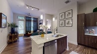 This thoughtfully designed single-floor residence offers a seamless blend of modern aesthetics and functional living. The open-concept layout connects the kitchen and living area, creating an expansive, airy feel enhanced by wood-look flooring that flows throughout the main spaces.

The kitchen is a standout feature, showcasing rich dark-toned cabinetry, granite countertops, a center island with an undermount sink and integrated dishwasher, stainless steel appliances including a French door refrigerator and gas range, and a sleek tile backsplash with under-cabinet lighting. Pendant lighting above the island and a track lighting system add both task and ambient illumination.

The living room is bright and welcoming, with tall ceilings, large windows dressed in elegant drape panels that invite natural light and outdoor views. A ceiling fan adds comfort, while the generous layout accommodates comfortable seating arrangements.

The bedroom offers a calm retreat, featuring plush carpeting, a large window with lush exterior views, and tasteful lighting. The bathroom is finished with light tile flooring, a dark wood double vanity with granite countertops, a wide mirror, and a full tub with shower combination. Every detail reflects a cohesive, contemporary design sensibility throughout.
