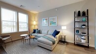 This well-designed single-floor residence blends modern aesthetics with functional living across a thoughtfully arranged floor plan. The living room is bright and welcoming, featuring large windows that invite natural light, warm hardwood-style flooring, and neutral tones complemented by tasteful artwork and contemporary furnishings. A dedicated media area with hardwood flooring adds versatility to the living space.

The kitchen is a standout feature, showcasing flat-panel cabinetry in a warm gray wood finish, white quartz countertops, a classic subway tile backsplash, and a full suite of stainless steel appliances including a gas range, dishwasher, microwave, and refrigerator. A kitchen island provides additional prep and dining space.

Both bedrooms are serene retreats with plush carpeting, generous window placement for natural light, and soft neutral wall tones. One bedroom features a custom walk-in closet outfitted with built-in shelving, hanging rods, and a sleek white drawer unit, offering excellent storage organization.

The two bathrooms mirror the home's modern design language, finished with large-format tile flooring, wood-toned vanity cabinetry, white countertops, and frameless glass shower enclosures. Clean lines and quality fixtures complete each space, contributing to an overall ambiance of understated elegance throughout the residence.
