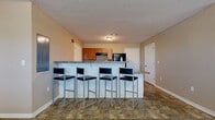 Located at 700 S Haverhill Rd in El Dorado, Kansas, this single-floor unit offers a practical and well-organized layout designed for comfortable everyday living. The kitchen is a standout feature, equipped with warm wood cabinetry, granite-style laminate countertops, black appliances including a gas range and full-size refrigerator, and durable tile flooring. A peninsula with bar-height seating for four provides a casual dining area that connects the kitchen to the main living space. The carpeted living room is generously sized, offering ample space for seating and relaxation, and is brightened by natural light from a window. A hallway connects the living area to the bedrooms, each of which features plush carpet flooring, neutral-toned walls, and windows that bring in natural light. The bedrooms offer sufficient space for a bed and study desk, making them well-suited for day-to-day use. The bathrooms include a vanity with wood cabinetry, a mirror, tile flooring, and a standalone walk-in shower unit with built-in shelving. Additional accessibility features, such as grab bars, are present in at least one bathroom. The unit also includes a laundry area, adding everyday convenience throughout this straightforward and functional space.