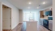 Located at 4311 Shoppers Lane in Columbus, Ohio, this single-floor residence offers a thoughtfully designed layout that maximizes every square foot. Consistent wood-look flooring flows throughout the entire space, creating a cohesive and modern aesthetic complemented by neutral gray walls and crisp white trim.

The combined kitchen and living area forms the heart of the home. The kitchen is well-appointed with rich, two-toned cabinetry, light granite countertops, a kitchen island, and a full suite of black Whirlpool appliances including a refrigerator, electric range, and over-the-range microwave. The adjacent living room is bright and airy, featuring a ceiling fan with light fixture and double windows that invite natural light and offer views of the surrounding neighborhood.

The bedroom is a comfortable retreat with multiple windows fitted with blinds, providing both natural light and privacy. A dedicated closet offers convenient storage. The full bathroom features a vanity with granite-style countertop, a large wall mirror, and warm cabinetry that ties in with the kitchen's design language. The clean, open layout of the bathroom reflects the same modern simplicity found throughout the home, making this residence a practical and attractive option in the Columbus area.