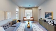 This thoughtfully designed single-floor residence offers a cohesive blend of modern style and functional living across its well-organized layout. The kitchen serves as a standout feature, showcasing crisp white cabinetry that extends to the ceiling for ample storage, granite countertops, stainless steel appliances, and a large central island with seating — all illuminated by elegant pendant lighting. Light wood-style flooring flows throughout the main living areas, adding warmth and continuity.

The living room is bright and welcoming, with large windows that invite natural light and offer views of the surrounding urban environment. The space is comfortably sized to accommodate both relaxed lounging and entertaining.

A dedicated dining nook provides an intimate setting for meals, featuring light wood flooring and clean wall lines accented by framed artwork. The bedrooms are carpeted for comfort, each offering generous closet space and large windows with urban views. The primary bedroom includes a walk-in closet and a well-organized dressing area.

The bathroom is finished with white cabinetry, a framed mirror, and light wood flooring, maintaining the clean, neutral palette found throughout the residence. Overall, the space presents a polished, contemporary atmosphere with consistent finishes and a calm, neutral color scheme.