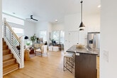 Located at 411 Charles Ave in Charlotte's vibrant Plaza Midwood neighborhood, this modern three-story home offers 2 bedrooms and 4 bathrooms across a thoughtfully designed layout. The ground floor provides a garage and entry, while the main living floor showcases a striking open-concept kitchen and living area. Soaring ceilings and large windows flood the space with natural light, highlighting wide-plank hardwood floors throughout. The kitchen is outfitted with crisp white cabinetry, quartz countertops, a bold dark-topped island with bar seating, stainless steel appliances, a black matte faucet, and a subway tile backsplash. Pendant lighting above the island adds a contemporary touch. The living area features oversized windows offering neighborhood views, with a ceiling fan completing the airy feel. Warm wood-tread stairs with clean white risers and a natural wood handrail connect all three floors. The upper level houses two well-appointed bedrooms, including a primary suite with dedicated closet space. The four bathrooms are elegantly finished, with one featuring geometric patterned tile flooring, a floor-to-ceiling tiled walk-in shower with glass door, and a dark stone vanity. A dedicated laundry room and utility space add practical convenience to this polished Charlotte home.