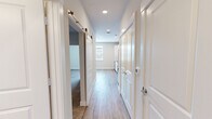 This efficiently designed one-bedroom, one-bathroom unit delivers a thoughtful layout that maximizes every square foot of its compact footprint. The open kitchen serves as a central highlight, featuring crisp white shaker cabinets, granite-style countertops, a subway tile backsplash, and a full suite of stainless steel appliances including a refrigerator, range, built-in microwave, and dishwasher — all set atop light wood-look luxury vinyl flooring that extends throughout the main living areas.

A well-proportioned hallway connects the living spaces, fitted with recessed lighting overhead and a stylish sliding barn door that adds a modern design touch. The hallway also provides access to in-unit laundry connections, adding everyday convenience.

The bedroom offers a comfortable retreat with plush wall-to-wall carpeting, a ceiling fan, and a window that brings in natural light. The room includes panel box access and connects seamlessly to the rest of the unit via the central corridor.

The bathroom is finished to a high standard, featuring a granite-topped vanity with white cabinetry, wood-look tile flooring, and a full tub-shower combination adorned with large-format marble-style tile surround. Clean, neutral tones throughout create a cohesive and modern aesthetic that feels fresh and move-in ready.