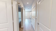 This efficiently designed one-bedroom, one-bathroom unit delivers a thoughtful layout that maximizes every square foot of its compact footprint. The open kitchen serves as a central highlight, featuring crisp white shaker cabinets, granite-style countertops, a subway tile backsplash, and a full suite of stainless steel appliances including a refrigerator, range, built-in microwave, and dishwasher — all set atop light wood-look luxury vinyl flooring that extends throughout the main living areas.

A well-proportioned hallway connects the living spaces, fitted with recessed lighting overhead and a stylish sliding barn door that adds a modern design touch. The hallway also provides access to in-unit laundry connections, adding everyday convenience.

The bedroom offers a comfortable retreat with plush wall-to-wall carpeting, a ceiling fan, and a window that brings in natural light. The room includes panel box access and connects seamlessly to the rest of the unit via the central corridor.

The bathroom is finished to a high standard, featuring a granite-topped vanity with white cabinetry, wood-look tile flooring, and a full tub-shower combination adorned with large-format marble-style tile surround. Clean, neutral tones throughout create a cohesive and modern aesthetic that feels fresh and move-in ready.