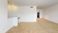 This single-floor unit offers a practical and comfortable layout designed to maximize functionality. The living area is finished with warm neutral carpeting and features crown molding along the ceiling, lending a clean, polished look to the space. White walls and a large window with blinds allow natural light to fill the room, creating a bright and open atmosphere. A dedicated laundry area with a stacked washer and dryer unit is conveniently accessible from the main living space.

The kitchen is equipped with honey-toned wood cabinetry, dark speckled laminate countertops, and a full suite of appliances including an electric range, built-in microwave, and dishwasher. Tile flooring completes the kitchen's practical and tidy aesthetic.

The bedroom continues the neutral carpeting found throughout the unit and includes crown molding, a window with blinds that brings in natural light, and ample wall space for furnishings.

The bathroom features a clean, all-white tub and shower combination with chrome fixtures and a towel bar, maintaining a simple and functional design. Overall, the unit presents a cohesive, move-in ready environment with consistent finishes throughout.