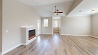 Located in D'Iberville, Mississippi, this two-story, 2-bedroom, 2-bathroom home offers a well-designed layout across two levels. The ground floor houses an attached garage with an automatic opener, providing convenient and secure parking. A staircase with wood-tread steps and clean white risers leads to the main living level above.

The upper floor is where daily life unfolds. The open-concept kitchen and living room area is a standout feature, with vaulted ceilings, a ceiling fan, and a modern electric fireplace anchoring the living space. Multiple windows invite natural light throughout. The kitchen is equipped with stainless steel appliances — including a refrigerator, range, and microwave — paired with white shaker cabinetry, a white countertop island with pendant lighting, and light wood-tone flooring.

Both bedrooms are carpeted and feature ceiling fans, windows with blinds offering natural light, and individual closets with wire shelving systems. The primary bedroom includes a generously sized walk-in closet. Both bathrooms are finished with white vanities, white quartz countertops, tiled tub-shower combinations, and light hardwood-style flooring, creating a clean, cohesive aesthetic throughout the home.