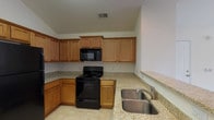 This single-floor residence in Summer Phase I offers a practical and well-appointed layout across two bedrooms and two bathrooms. The kitchen is a functional centerpiece, featuring warm honey-toned cabinetry with crown molding details, granite-style countertops, tile flooring, and a full suite of black appliances including a range, over-the-range microwave, dishwasher, and refrigerator. A double stainless steel sink adds to the kitchen's utility.

Both bedrooms are carpeted and receive natural light through windows with blinds. Ceiling fans with integrated lighting fixtures are present in the bedrooms, contributing to comfort year-round. At least one bedroom includes access to a walk-in closet equipped with wire shelving for organized storage.

Each bathroom features tile flooring, a soaking tub-shower combination, granite-style vanity countertops, and wood-toned cabinetry. A dedicated laundry room with tile flooring, wire shelving, washer and dryer connections, and an electrical panel provides added convenience. The overall aesthetic is clean and neutral throughout, with white walls and light-toned finishes creating a bright, welcoming atmosphere.