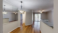 Located at 912 Meadow Creek Dr in Irving, TX, this two-bedroom, one-bathroom residence offers a well-organized single-floor layout. The open-concept living and dining area is anchored by warm hardwood flooring and crown molding throughout, with a pendant light fixture adding a refined touch above the dining space. A large sliding glass door floods the living area with natural light and opens to a private balcony overlooking mature trees, creating a seamless indoor-outdoor connection.

The kitchen features white cabinetry, granite-style countertops, stainless steel appliances including a refrigerator, range, and microwave, and a peninsula that separates it from the dining area. A large mirror panel in the dining space enhances the sense of openness.

Both bedrooms are carpeted and include ceiling fans, crown molding, and ample natural light from windows with blinds. The primary bedroom features a mirrored sliding-door closet, while a separate walk-in closet with wire shelving provides additional storage. The shared bathroom offers a corner vanity with granite-style countertops, white cabinetry, and hardwood flooring. Textured ceilings are present throughout the residence.