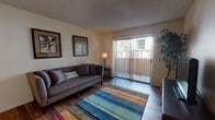 Located at 1901 N Wilmot Rd in Tucson, Arizona, this single-story unit offers a practical and comfortable layout with well-defined living spaces throughout. The living room serves as the heart of the home, featuring warm hardwood-style flooring, a textured ceiling, and a full-width sliding glass door fitted with vertical blinds that opens to a private outdoor balcony, allowing natural light to filter in and providing pleasant exterior views.

Adjacent to the living area, the galley-style kitchen is equipped with warm wood cabinetry lining both walls, laminate countertops, a full-size refrigerator, and an electric range with overhead ventilation. The hardwood-style flooring continues through the kitchen, maintaining a cohesive aesthetic.

The bedroom is carpeted for comfort and features multiple windows with vertical blinds that bring in natural light. A walk-in closet provides ample storage space, making the room both functional and restful.

The bathroom is notably spacious, showcasing an extended dual-sink vanity with a light countertop, wood-toned cabinetry below, and a large wall mirror that enhances the sense of space. The overall ambiance of the unit is warm and understated, with neutral wall tones throughout creating a clean, inviting atmosphere.