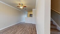 This two-story home offers a thoughtfully designed layout spread across two floors, providing comfortable living for everyday needs. The main level features a generous living room finished with durable wood-look flooring, crown molding, and a ceiling fan, creating a bright and welcoming atmosphere. Adjacent to the living room, the galley-style kitchen is well-equipped with dark cabinetry, light countertops, tile flooring, and black appliances including a gas range and refrigerator, alongside ample counter and storage space. A staircase connects the main level to the upper floor, where three carpeted bedrooms are located. The primary bedroom includes a walk-in closet and a ceiling fan, while the additional bedrooms also feature closets and ceiling fans. The two bathrooms are finished consistently with dark cabinetry, light countertops, and wood-look flooring, with one featuring a tub-shower combination. Three closets throughout the home provide generous storage. Completing the layout is a two-car garage with an automatic opener, offering secure and convenient parking. The home's consistent use of neutral tones, wood-look flooring, and dark cabinetry accents creates a cohesive and functional aesthetic throughout.