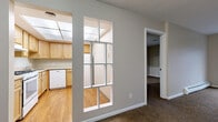 Located at 770 Maple Rd in Buffalo, NY, this single-floor unit offers a practical and comfortable layout with a variety of well-appointed spaces throughout. The kitchen is outfitted with warm honey-toned wood cabinetry, light laminate flooring, a full-size refrigerator, a dishwasher, and generous counter space. A distinctive multi-pane pass-through window connects the kitchen to the adjoining living area, enhancing the sense of openness between rooms. The living area is carpeted and features large sliding glass doors that open onto a private balcony, allowing natural light to fill the space and providing outdoor views of the surrounding neighborhood. Baseboard heating is present throughout, ensuring year-round comfort. The bedroom is carpeted and includes a closet with a rod for hanging storage, with a hallway leading to additional rooms. A second carpeted room with a dedicated window brings in natural light and offers flexible use as a bedroom or office. The bathroom is finished with a white vanity, integrated sink, ample under-sink storage, and a large mirror. Neutral-toned walls and clean white trim carry consistently throughout the unit, creating a cohesive and understated aesthetic well-suited for everyday living.