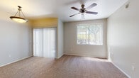 Located at 3980 W Linda Vista Blvd in Tucson, Arizona, this single-story residence offers a practical and well-organized layout designed for comfortable living. The open-concept living area is finished with plush carpet flooring and features ceiling fans for year-round comfort. Large windows and a sliding glass door fitted with vertical blinds allow natural light to fill the space while providing outdoor access and views of the surrounding landscape. A pendant light fixture adds a warm accent to the living area. The kitchen is a standout feature, showcasing rich cherry wood cabinetry, granite-style countertops, a decorative tile backsplash, and black appliances including a range, microwave, and dishwasher. Wood-look flooring extends through the kitchen, adding a warm contrast to the carpeted areas. A pass-through counter connects the kitchen to the main living space, enhancing the open feel. The bedrooms are generously sized, each with carpet flooring, ceiling fans, and ample natural light from well-placed windows. The bathrooms are cleanly finished with wood-look flooring, warm cabinetry with granite-style countertops, large mirrors, and tub-shower combinations — one featuring a soaking tub with tiled surround. The overall ambiance is neutral, clean, and move-in ready.
