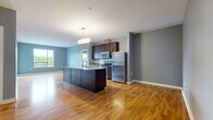 Located at 300 Riverboat Row in Newport, Kentucky, this well-appointed 2-bedroom, 2-bathroom residence offers a thoughtfully designed single-level layout. The open-concept living area seamlessly connects the kitchen, dining, and living spaces, all finished with warm hardwood flooring throughout. The kitchen is a standout feature, showcasing rich dark wood cabinetry, granite countertops, a large center island with a built-in sink, and a full suite of stainless steel appliances including a refrigerator, range, and microwave. Neutral gray walls provide a clean, modern backdrop throughout the home. The spacious primary bedroom includes a generous walk-in closet with built-in shelving and clothing rods, while both bedrooms offer plush carpet and large windows that allow natural light and outdoor views. The bathrooms are finished with dark tile flooring, dark wood vanities with granite countertops, and large mirrors. A carpeted hallway connects the private quarters of the home. Additional conveniences include an in-unit laundry room with a stacked washer and dryer, a water heater, and HVAC equipment. A private balcony rounds out this well-equipped residence in the heart of Newport.