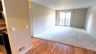 This single-floor home offers a well-organized layout with a blend of warm hardwood flooring and plush carpeting throughout its living spaces. The main living area is generously proportioned, with soft carpet underfoot and a large sliding glass door that floods the space with natural light and provides views of the surrounding greenery, making it feel open and inviting. Adjacent to the living area, a transition to hardwood flooring leads toward the dining and kitchen zones. A pendant light fixture adds a touch of character to this transitional space, which also features a built-in shelving unit, ideal for storage or display. The kitchen is well-appointed with rich, dark espresso cabinetry, granite countertops, and stainless steel appliances including a range and dishwasher, offering both style and functionality. The bedrooms are carpeted and bathed in natural light through large windows that frame views of mature trees outside, creating a calm and restful atmosphere. Each bedroom provides a comfortable, private retreat. Overall, the space presents a clean, neutral palette with warm tones throughout, offering a versatile and move-in ready environment suitable for a variety of living arrangements.