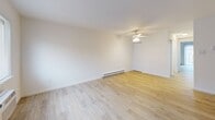 Located at 2835 Century Ln in Bensalem, PA, this one-bedroom, one-bathroom unit offers a well-organized, single-floor layout with a clean, bright aesthetic throughout. Light wood-style flooring flows continuously across all rooms, complemented by crisp white walls and white trim that give the space a fresh, airy feel.

The combined kitchen and living area forms the heart of the unit. The kitchen is well-appointed with warm honey-toned cabinetry extending to the upper walls, granite-style countertops, a tile backsplash, and a full suite of white appliances including a refrigerator, dishwasher, range, and microwave. The adjacent living area is generously sized, featuring a sliding glass door that floods the room with natural light and provides outdoor access. A wall-mounted air conditioning unit and baseboard heating ensure year-round comfort.

The bedroom is a comfortable, well-proportioned room with a closet, a ceiling fan, and a window that brings in additional natural light. Baseboard heating keeps the room consistently warm.

The bathroom features a clean, white tile tub-shower combination, a toilet, and a single vanity, all presented in a simple and functional layout. A staircase with a black metal railing is also visible, suggesting access to an additional level or shared building area. The overall ambiance is clean, neutral, and move-in ready.