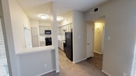 Located at Gatwick Circle in Fort Worth, TX 76155, this single-floor unit offers a well-designed layout with a clean, modern aesthetic throughout. The kitchen is a standout feature, showcasing gray shaker-style cabinetry, white quartz-style countertops, a classic white subway tile backsplash, and a full suite of black appliances including a range, over-the-range microwave, and refrigerator. Wood-look plank flooring runs through the kitchen and main hallway areas, while a peninsula-style breakfast bar visually connects the kitchen to the adjacent living space. The living area is carpeted and benefits from natural light provided by a large window fitted with horizontal blinds. The bedroom features plush carpet, a ceiling fan with light fixture, a double-door closet, and a window that allows additional natural light to fill the room. A second carpeted room with a bright window offers flexible use as an additional bedroom or living space. The bathroom is neatly appointed with gray cabinetry, a large vanity mirror, brushed nickel fixtures, a single-basin sink with marble-style countertop, wood-look flooring, and a full tub and shower combination. Textured ceilings are consistent throughout the unit, and the hallway features wall sconce lighting for a warm, welcoming ambiance.