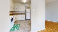 This 2-bedroom, 1-bathroom unit is thoughtfully organized across a single floor, offering a practical and comfortable layout. The interior is unified by warm, patterned parquet flooring that runs throughout the main living areas and both bedrooms, lending the space a classic, timeless character.

The spacious living area is a standout feature, benefiting from large windows that frame views of the surrounding urban skyline and allow generous natural light to fill the room. A baseboard heating system runs along the perimeter, ensuring year-round comfort.

The primary bedroom is a well-proportioned retreat, complete with a double-door closet for ample storage and access to natural light through its own window with city views. The second bedroom mirrors this layout with its own closet and window overlooking the cityscape.

The kitchen is efficiently designed with white cabinetry, dark countertops, a double sink, and white appliances including a refrigerator and stove, all set on neutral tile flooring. The bathroom features full-height tile surrounding a soaking tub with a shower curtain, complemented by clean white fixtures and tile flooring.

Two hallways connect the rooms, providing a logical flow throughout the unit. The overall aesthetic is clean, bright, and neutral, offering a versatile canvas for personalization.
