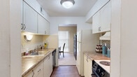 This single-floor, 2-bedroom, 1-bathroom residence offers a thoughtfully organized layout across a comfortable footprint. The galley-style kitchen is efficiently designed with white cabinetry, laminate countertops, a tile backsplash, and hardwood-style flooring. Equipped with a full suite of appliances, the kitchen opens directly into the dining area, creating a natural flow for everyday living and entertaining.

The dining room features a chandelier overhead, a bold green accent wall, and a sliding glass door fitted with vertical blinds that invite natural light. Adjacent to it, the spacious living room is a standout space with a vibrant teal accent wall, plush carpeting, and a relaxed, open atmosphere. A second sliding glass door brings in additional light and outdoor views.

The primary bedroom is generously sized and includes a ceiling fan, soft carpeting, a large sliding glass door, and a dedicated closet. The second bedroom is equally well-appointed. Three closets throughout the unit provide ample storage.

The full bathroom is clean and functional, featuring a tub-shower combo, a single-sink vanity with white cabinetry, and hardwood-style flooring. A utility room rounds out the layout, adding practical convenience. A hallway connects the private and shared spaces seamlessly throughout the home.