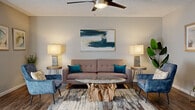 Located at 505 W Baseline Rd in Tempe, Arizona, this single-floor residence offers a thoughtfully designed layout with contemporary finishes and a cohesive aesthetic throughout. The living area serves as the heart of the home, showcasing warm hardwood-style flooring, a textured ceiling with a ceiling fan, and neutral walls that create a calm, inviting atmosphere. A mid-century modern sofa anchors the space, complemented by velvet accent chairs, a striking live-edge glass coffee table, and curated artwork that adds a touch of personality.

The kitchen is well-appointed with two-tone cabinetry — white upper cabinets paired with soft grey lowers — and light quartz countertops. Stainless steel appliances, including a refrigerator, range, and dishwasher, provide full functionality. The adjacent dining area comfortably accommodates a full dining table and benefits from natural light streaming through nearby windows.

A dedicated entryway with decorative accents and a compass wall mural provides a welcoming transition into the living space. The bathroom features grey vanity cabinetry with gold hardware, wood-look flooring, and a glass-enclosed shower. Additional storage is available through a carpeted closet space. The overall design balances modern sensibility with warm, eclectic touches throughout.