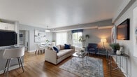 This single-floor residence offers a thoughtfully designed open-concept layout that seamlessly connects the main living spaces. The living room is anchored by warm wood-look flooring, soft grey walls, and a textured ceiling, with large windows that invite generous natural light. A glass-top coffee table and a plush area rug define the central seating area, while a dedicated nook accommodates a cozy accent chair and side table.

The dining area sits adjacent to the living room, featuring a glass-top table with modern white chairs beneath a pendant light, framed by vertical blinds and an oversized abstract art piece on the wall.

The kitchen features white cabinetry, granite-look countertops, a peninsula with bar seating, a stainless sink, and black appliances — offering both functionality and style. Wood-look flooring carries throughout.

The primary bedroom provides a calm, comfortable retreat with warm neutral tones, natural light from a window with sheer curtains, and wood-look flooring. A secondary bedroom is well-sized with a closet and playful character. A flexible room serves well as a home office or sitting area.

The bathroom includes a soaking tub and shower combination with full-height subway tile surround and neutral floor tile, creating a clean, classic finish throughout.