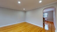 This two-floor residence offers a thoughtfully arranged layout with consistent design details throughout. Warm hardwood flooring runs through the majority of the space, lending a cohesive and inviting character to each room. Neutral gray walls provide a clean, versatile backdrop across all living areas.

The main living areas are bright and open, benefiting from recessed lighting and crown molding that adds a refined architectural touch. Elegant arched doorways connect key areas of the home, adding a classic design element to the overall aesthetic. Baseboard radiators beneath windows provide heating throughout the bedrooms, which are well-proportioned and filled with natural light from double-hung windows fitted with blinds.

The kitchen is well-equipped with warm wood cabinetry, light granite-style countertops, a tile backsplash, and tile flooring. It features a gas range, dishwasher, and over-the-range microwave, along with a double sink and a door leading directly outside, offering convenient access.

A hallway on the upper level connects the bedrooms to a full bathroom, which includes a tub-shower combination, white tile flooring, and a pedestal sink. The layout of the home is practical and efficient, with a welcoming entry area featuring another arched passage leading into the main living space.