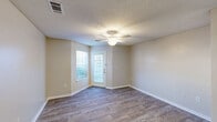 Located at 504 Forest Cir in Walterboro, South Carolina, this single-floor, one-bedroom, one-bathroom home offers a practical and well-organized layout. The open-concept living, dining, and kitchen area forms the heart of the home, featuring durable wood-look flooring, neutral beige walls, and a textured ceiling. The living room is bright and airy, with natural light streaming through a glass-paneled front door and an adjacent window, complemented by a ceiling fan with a built-in light fixture. A dedicated dining area is defined by a classic brass chandelier, adding a touch of warmth to the space. The kitchen includes wood-trimmed white cabinetry, a white electric range, refrigerator, and ample counter space, along with a pantry for additional storage. The bedroom offers carpeted flooring, a ceiling fan, a window with outdoor views, and access to a closet. The bathroom features a wide vanity with an extended countertop, under-sink storage, and a large mirror with overhead lighting. Additional functional spaces include a laundry area and a utility room, making this home both efficient and comfortable for everyday living.