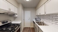 This one-bedroom, one-bathroom residence at The Mississippi in Memphis, Tennessee offers a well-designed single-level layout with a blend of practical finishes and comfortable living spaces. The living area is bright and open, featuring dark hardwood-style flooring and a large sliding glass door that fills the room with natural light and provides access to an outdoor balcony with city views. A distinctive pass-through window connects the living area to the kitchen, enhancing the sense of openness between the two spaces. The galley-style kitchen is efficiently designed with white shaker cabinetry, white countertops, a classic subway tile backsplash, stainless steel appliances including a gas range, and a double-basin stainless steel sink. Hardwood-style flooring continues throughout the kitchen, complementing its clean, modern aesthetic. The bedroom is generously proportioned, featuring plush wall-to-wall carpeting, a ceiling fan with light fixture, a natural light-admitting window, and a roomy closet with a clothes rod. The full bathroom includes a combined tub and shower, a toilet, and hardwood-style flooring, finished in a clean, neutral palette. Throughout the unit, neutral wall tones and consistent flooring create a cohesive and move-in ready environment.
