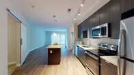 This single-floor residence offers a thoughtfully designed layout that balances open communal spaces with private quarters. The kitchen serves as a central highlight, featuring dark espresso cabinetry extending to the ceiling, stainless steel appliances including a range, microwave, dishwasher, and refrigerator, complemented by a classic white subway tile backsplash and granite-look countertops. A kitchen island with a butcher block-style surface provides additional workspace and flows seamlessly into the open living area, which is finished with rich hardwood-style flooring and large sliding glass doors that invite abundant natural light.

The bedrooms offer generous proportions, finished with neutral carpet and multiple windows fitted with blinds. Closet space is provided via wire-rack systems, offering practical storage. The bathrooms are finished with large-format neutral tile, featuring tub-shower combinations with glass enclosures and dark wood floating vanities with undermount sinks. Neutral wall tones and clean white trim throughout the space contribute to a cohesive, contemporary aesthetic. The 3D floor plan reveals a well-organized layout with efficient use of space across all rooms.