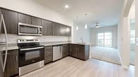 This 1-bedroom, 1-bathroom unit offers a thoughtfully designed single-floor layout that maximizes functionality throughout. The open-concept kitchen flows seamlessly into the living area, creating a connected and versatile space. The kitchen is outfitted with dark wood-grain cabinetry, granite-style countertops, white subway tile backsplash, and a full suite of stainless steel appliances including a refrigerator, range, microwave, and dishwasher. Light wood-style flooring runs through the kitchen and hallway, lending a clean, modern aesthetic. The living room features plush carpeting, a ceiling fan, and a sliding glass door that opens to a private balcony, filling the space with natural light and outdoor views. The bedroom is a comfortable, carpeted retreat with a ceiling fan, a window with natural light, and direct access to a generous walk-in closet equipped with wire shelving and built-in shelving units for ample storage. The bathroom continues the modern design language with matching dark cabinetry, granite-style countertops, light wood-style flooring, and a full tub-shower combination. Elegant arched doorways in the hallway add a subtle architectural charm throughout the unit.