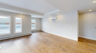 Located on Walker Avenue in Halifax, Nova Scotia, this modern 2-bedroom, 2-bathroom residence offers a thoughtfully designed single-floor layout with generous living space. The open-concept kitchen and living area serves as the heart of the home, featuring striking navy and light wood cabinetry, a large centre island with a double undermount sink and white quartz countertops, stainless steel appliances including a built-in range and refrigerator, and recessed pot lighting overhead. Warm, wide-plank hardwood flooring flows consistently throughout the entire unit, complementing the clean, neutral palette of the walls and trim. The spacious living room benefits from natural light through large windows and includes a wall-mounted mini-split heating and cooling unit for year-round comfort. The primary bedroom is generously sized, with dedicated closet storage. Both bathrooms are finished with large-format tile, modern vanities with white countertops, and light wood cabinetry. One bathroom features a soaker tub with a tiled shower surround, while the second offers a glass-enclosed walk-in shower. Two closets provide ample storage throughout the unit. The overall design is clean, contemporary, and move-in ready.