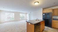 Located at 104 Merchant Ave in Mount Joy, PA, this single-floor residence offers 2 bedrooms and 2 bathrooms within a well-organized, functional layout. The open-concept living and kitchen area forms the heart of the home, where warm honey-toned cabinetry, dark countertops, and black appliances — including a refrigerator, range, and microwave — define the kitchen. A peninsula with a built-in sink and dark countertop provides additional workspace and connects seamlessly to the carpeted living area. Large windows throughout the living space allow generous natural light and offer views of the surrounding neighborhood greenery. The spacious primary bedroom features plush carpeting, multiple windows, a closet, and direct access to a private en-suite bathroom equipped with a walk-in shower. The second bedroom is also generously sized, well-lit with multiple windows, and finished with soft carpeting. The second bathroom includes a full tub-shower combination and tile flooring. Both bathrooms are finished with clean, neutral tones. Tile flooring extends through the kitchen and bathrooms, while plush carpet covers the living and bedroom areas, creating a warm and comfortable atmosphere throughout.