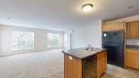 Located at 104 Merchant Ave in Mount Joy, PA, this single-floor residence offers 2 bedrooms and 2 bathrooms within a well-organized, functional layout. The open-concept living and kitchen area forms the heart of the home, where warm honey-toned cabinetry, dark countertops, and black appliances — including a refrigerator, range, and microwave — define the kitchen. A peninsula with a built-in sink and dark countertop provides additional workspace and connects seamlessly to the carpeted living area. Large windows throughout the living space allow generous natural light and offer views of the surrounding neighborhood greenery. The spacious primary bedroom features plush carpeting, multiple windows, a closet, and direct access to a private en-suite bathroom equipped with a walk-in shower. The second bedroom is also generously sized, well-lit with multiple windows, and finished with soft carpeting. The second bathroom includes a full tub-shower combination and tile flooring. Both bathrooms are finished with clean, neutral tones. Tile flooring extends through the kitchen and bathrooms, while plush carpet covers the living and bedroom areas, creating a warm and comfortable atmosphere throughout.