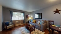 Located on Aster Street in Springfield, Oregon, this two-floor residence offers a well-organized layout designed for comfortable, everyday living. The main level features an open living and dining area finished with warm wood-style flooring throughout. The living room is bright and welcoming, benefiting from a large window that draws in natural light and provides views of the surrounding greenery. A wall-mounted air conditioning unit ensures year-round comfort. The dining area sits just off the living space, creating a seamless flow ideal for both relaxing and entertaining.

The kitchen is efficiently laid out with ample white cabinetry, granite-style countertops, and black appliances including a full-size refrigerator and electric range. Recessed lighting keeps the space well-lit and functional.

The bathroom is finished with wood-style flooring, a granite-topped vanity, and a full tub-shower combination. A standout convenience is the inclusion of an in-unit washer located within the bathroom area, along with built-in overhead storage cabinetry.

The bedroom, situated on the upper level, features plush carpeting, a window with natural light, and a baseboard heating system. The second floor layout, as seen in the dollhouse view, also includes additional rooms accessible via an interior staircase, offering versatile use of space throughout the home.