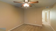 This two-floor residential space offers a straightforward and functional layout suited for everyday living. The interior is finished with wall-to-wall carpeting that adds warmth and comfort underfoot, complemented by neutral-toned walls that create a clean, understated backdrop throughout. Ceiling fans with integrated light fixtures are present in the living areas, providing both air circulation and ambient lighting. White baseboards provide a crisp contrast against the carpeted floors and painted walls, contributing to a tidy, classic look. The open corner layout visible in the main living area suggests a generous sense of space, offering flexibility for a variety of furniture arrangements. Natural light filters in through windows, brightening the interior and adding to the overall livable ambiance. Spanning two floors, the home provides separation between living and private spaces, a practical feature for households seeking distinct zones for activity and rest. The overall aesthetic is simple and move-in ready, offering a neutral canvas that can be personalized to suit a variety of styles and preferences.