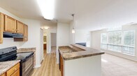 This one-bedroom, one-bathroom unit at 229 Lake Club Court in Charlottesville, Virginia offers a well-organized layout across a single floor. The kitchen serves as a central feature, equipped with warm wood cabinetry, granite-style countertops, black appliances including a refrigerator and electric range, and a peninsula with a built-in sink and pendant lighting overhead. Light hardwood-style flooring runs through the kitchen and entry areas, creating a clean transition into the living space.

The living room is carpeted and benefits from abundant natural light through multiple windows, a ceiling fan, and a set of French doors that open onto a private balcony overlooking lush, wooded surroundings. This outdoor connection adds a sense of openness to the living area.

The bedroom is comfortably sized with soft carpet flooring and direct access to a walk-in closet featuring built-in shelving and hanging rods. The bathroom includes a soaking tub and shower combination with tiled surround and chrome fixtures. In-unit laundry adds everyday convenience. The overall ambiance is bright, neutral, and functional throughout.