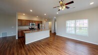 This single-floor residence offers a thoughtfully designed layout that balances open communal spaces with comfortable private quarters. The heart of the home is an open-concept kitchen and living area, where rich wood-look flooring flows seamlessly underfoot. The kitchen is equipped with stainless steel appliances—including a refrigerator, range, and over-the-range microwave—complemented by warm wood cabinetry, granite-style countertops, and a central island with a sink, ideal for both meal preparation and casual dining. Recessed lighting and a ceiling fan keep the space bright and comfortable, while sliding glass doors and multiple windows invite abundant natural light and outdoor views into the adjacent living area.

The bedrooms feature plush carpeting, ceiling fans, and generous natural light from well-placed windows, creating a calm and restful atmosphere. Two full bathrooms serve the residence; one includes a double-sink vanity with granite-style counters, a walk-in shower, and wood-look flooring, while the second offers a combined tub and shower with a similar warm aesthetic. Warm neutral tones, clean white trim, and consistent finishes throughout give the entire space a cohesive, move-in-ready feel.