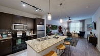 Located at 390 Stovall St SE in Atlanta's vibrant Grant Park neighborhood, this well-appointed one-bedroom, one-bathroom residence offers a thoughtfully designed open-concept layout across a single floor. The combined kitchen and living area serves as the heart of the home, anchored by a granite-topped kitchen island with a double sink and seating for casual dining. Dark espresso cabinetry, a subway tile backsplash, stainless steel appliances including a refrigerator and microwave, and track lighting overhead give the kitchen a clean, contemporary feel. Pendant lights above the island add a warm, inviting touch. The living area flows naturally from the kitchen and is bathed in natural light from large windows dressed with blinds and draping curtains. Wood-style flooring runs throughout, tying the spaces together cohesively. The bedroom is a serene retreat highlighted by a striking full-wall watercolor mural in deep blues, wood-style flooring, and generous natural light from oversized windows. A dedicated closet and in-unit laundry room with side-by-side washer and dryer add everyday convenience. The bathroom features a tub-shower combination with white tile surround, a dark vanity with an integrated sink, and neutral tile flooring, completing this efficient and stylishly modern residence.