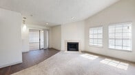 This single-floor, 3-bedroom, 1-bathroom home offers a well-organized layout with a comfortable blend of functional design and practical finishes. The living room serves as the heart of the home, featuring a tile-surround wood-burning fireplace and large windows fitted with blinds that allow natural light to fill the carpeted space. Sliding glass doors provide access to an outdoor area, adding to the sense of openness. The kitchen is positioned adjacent to the living area and is defined by dark gray cabinetry, a mosaic tile backsplash, a breakfast bar, stainless steel appliances including a microwave and range, and track lighting overhead. The three bedrooms are carpeted and well-lit, with windows bringing in ample natural light. The primary bedroom features a ceiling fan and direct access to a walk-through closet and the shared bathroom. One additional bedroom includes a dedicated closet with built-in shelving, while another benefits from tall ceilings and a large corner window. The bathroom is finished with dark vanity cabinetry, white countertops, mosaic tile accents, a framed mirror, and a tiled tub-shower combination with wood-look flooring. A hallway with two closets connects the main spaces efficiently throughout the home.
