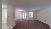 Located at 6330 Orchard Club Dr in Elkridge, Maryland, this well-laid-out single-floor residence offers a practical and comfortable living environment throughout its thoughtfully arranged spaces. The open living and dining area is generously sized, featuring plush dark carpeting, neutral cream-toned walls, and a pendant light fixture. A glass-paneled door leads to an outdoor balcony, while an adjacent window allows natural light and views of surrounding greenery to fill the space. The kitchen is equipped with warm wood cabinetry, granite-style countertops, tile flooring, and black appliances including a full-size refrigerator, providing ample functionality. A hallway connects the main living area to the private quarters, which include well-proportioned carpeted bedrooms, each with windows offering natural light. The bedrooms feature six-panel closet doors providing generous storage. Two full bathrooms are present, each featuring a tiled tub-shower combination with a classic white-and-tan tile accent stripe, tile flooring in warm earth tones, and a vanity with cabinetry. Throughout the residence, a consistent design palette of neutral tones and practical finishes creates a clean, move-in ready atmosphere suited for comfortable everyday living.