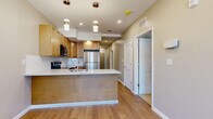 This well-designed two-bedroom, two-bathroom residence in Webster, NY offers efficient single-floor living with a thoughtful layout and modern finishes throughout. Light hardwood flooring runs through the main living areas, complemented by neutral-toned walls and recessed lighting that create a bright, welcoming ambiance.

The kitchen serves as a central hub of the home, featuring warm maple cabinetry, a classic white subway tile backsplash, light quartz countertops, and a full suite of stainless steel appliances including a refrigerator, electric range, and over-the-range microwave. A peninsula with pendant lighting provides additional prep space and connects seamlessly to the combined dining and living area.

A clean hallway lined with three closets links the main living space to the private quarters, offering ample storage throughout. Both bedrooms are carpeted for comfort and feature neutral walls and natural light from windows with views of the surrounding greenery. The primary bedroom is a well-proportioned retreat with its own dedicated closet access.

Both bathrooms are finished with marble-style tile flooring, white quartz vanity tops, dark wood cabinetry, and chrome fixtures, delivering a clean, contemporary aesthetic. An in-unit laundry area adds further convenience to this practical and polished home.