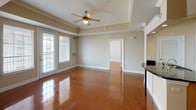 This single-story residence presents a cohesive design highlighted by richly polished, stained concrete floors that flow throughout every room, lending warmth and a distinctive character to the entire space. The open-concept layout seamlessly connects the living area to the kitchen, promoting an expansive, airy feel. The living room features a tray ceiling with crown molding and a ceiling fan, adding architectural depth, while large windows fitted with blinds allow generous natural light to fill the space.

The kitchen is well-appointed with light maple cabinetry offering abundant storage, dark granite countertops, a stainless steel sink, and black appliances including a range, microwave, and refrigerator. A kitchen island with matching granite provides additional workspace and visual interest.

The bedrooms are comfortably sized, each equipped with ceiling fans and windows that bring in natural light. The bathrooms are finished with the same dark granite countertops, light maple vanity cabinetry, large mirrors, and well-lit vanity fixtures. One bathroom includes a tub-shower combination with full white tile surround and direct access to a walk-in closet. The overall palette of warm beige walls and consistent finishes creates a unified, functional living environment.