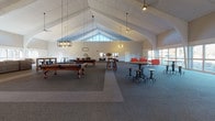 This single-story clubhouse is defined by its striking architectural design, highlighted by soaring vaulted ceilings with white-painted wood paneling and prominent arched structural beams that lend the space a grand, open feel. Large floor-to-ceiling windows line the walls, flooding the interior with abundant natural light and offering picturesque views of the surrounding wooded landscape.

The main gathering area features a classic brick fireplace topped by a wall-mounted flat-screen television set against a bold navy blue accent wall, creating a natural focal point. Generous seating is arranged throughout, including plush sofas, colorful bean bag chairs, and a children's activity table, making the space welcoming for all ages. A central high-top table with bar stools serves as a casual gathering spot alongside two full-size pool tables.

A separate lounge area is furnished with vibrant teal and mustard accent chairs, a tufted sofa, and colorful artwork, providing a more intimate setting. An additional open area offers flexible space with high-top seating, a whiteboard, and beverage stations, suitable for events or gatherings. Industrial-style pendant lighting and ceiling fans complement the overall aesthetic. Throughout, neutral carpeting unifies the various zones, while the vaulted ceiling and abundant windows contribute to the bright, airy ambiance of this well-appointed clubhouse.