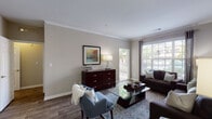 Located at 1525 Grayson Hwy in Grayson, GA, this single-story, one-bedroom, one-bathroom residence offers a well-designed layout with thoughtful finishes throughout. The living area is bright and welcoming, featuring hardwood-style flooring, crown molding, and neutral warm-toned walls that create a clean, cohesive aesthetic. Large windows fitted with blinds and curtain panels invite natural light, while a sliding glass door opens directly onto a private balcony with outdoor views. The kitchen is efficiently organized with ample white cabinetry, dark countertops, a tile backsplash, and full appliances including an electric range and refrigerator — all set on matching hardwood-style flooring. The bedroom is a calm retreat with plush carpeting, a large window for natural light, and convenient access to both a walk-in closet and the full bathroom. The bathroom features a white vanity with dark countertop, a combined tub and shower, and wood-style flooring that ties the space together. Crown molding in the living area adds a refined architectural touch, while the overall layout maximizes functionality and comfort throughout this well-appointed Grayson residence.