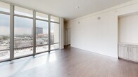 Located at 3120 Smith St in Houston's vibrant Montrose neighborhood, this generously sized 2-bedroom, 2-bathroom residence offers a thoughtfully designed open-concept layout with modern finishes throughout. The combined living, dining, and kitchen area serves as the heart of the home, anchored by dramatic floor-to-ceiling windows that flood the space with natural light and frame sweeping city views. A private balcony extends the living area outdoors, offering elevated vistas of the Houston skyline.

The kitchen features light wood cabinetry, white quartz countertops, a central island, stainless steel appliances including a dishwasher, and pendant lighting overhead. A built-in wine cooler adds a refined touch to the dining area. Wide-plank hardwood-style flooring runs throughout the main living spaces and bedrooms, complemented by crisp white walls and ceiling fans in each bedroom.

The primary bedroom suite includes a walk-in closet and an en-suite bathroom with a soaking tub, large mirror, and light wood vanity. The second bathroom offers a full tub-shower combo with clean tile finishes. A dedicated laundry room houses a full-size washer and dryer. The overall aesthetic is clean, contemporary, and bright.