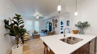 Located in South Jordan, Utah, this single-floor residence offers a well-designed open-concept layout that seamlessly connects the kitchen, dining, and living areas. The kitchen is a standout feature, equipped with dark walnut cabinetry, white quartz countertops, stainless steel appliances, and a generously sized island with seating for multiple bar stools — all illuminated by modern pendant lighting. Light wood-style flooring runs throughout the main living areas, contributing to a clean and contemporary aesthetic.

The living room is bright and inviting, benefiting from abundant natural light through large windows with plantation-style blinds. A ceiling fan adds a practical touch, while a glass door provides access to the exterior. The space is both comfortable and versatile in its layout.

Two well-proportioned bedrooms offer plush carpeting, ample natural light, and a calm, neutral color palette. Each room provides a restful retreat with clean white walls and window blinds for privacy.

The bathroom is finished with wood-toned cabinetry, white quartz countertops, light wood flooring, and a full tub-shower combination. Throughout the residence, the design maintains a cohesive modern style, balancing functionality with a refined, welcoming atmosphere.