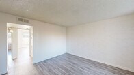 Located at 7440 East Thomas Road in Scottsdale, Arizona, this single-floor, 2-bedroom, 1-bathroom residence offers a clean, neutral design with a cohesive aesthetic throughout. Light-toned luxury vinyl plank flooring runs continuously across all rooms, complementing the white textured walls and adding a modern, low-maintenance quality to the space.

The living room serves as the main gathering area, featuring a sliding glass door fitted with vertical blinds that allows natural light to pour in and provides access to an outdoor patio area with views of surrounding greenery. A front entry door alongside a window further brightens this welcoming space.

The two bedrooms are well-proportioned, with the primary bedroom offering a comfortable footprint. Each bedroom features the same consistent flooring and neutral wall finishes, with windows dressed in vertical blinds to control light and privacy. A hallway connects the rooms and includes a closet for additional storage.

The full bathroom is outfitted with a tub-shower combination featuring white tile surround, a single-sink vanity with a speckled stone-look countertop and a dark cabinet base, and wood-look flooring that ties in with the rest of the home. Brushed gold and chrome fixtures add a subtle, contemporary accent throughout the bathroom.