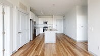 Located at 1184 Hank Aaron Dr in Atlanta, GA, this thoughtfully designed 2-bedroom, 2-bathroom residence offers a clean, contemporary aesthetic throughout its single-floor layout. The open-concept living area seamlessly connects the kitchen, dining, and living spaces, creating an airy and functional environment. The kitchen is a standout feature, equipped with stainless steel appliances including a refrigerator, range, and microwave, complemented by crisp white cabinetry, light stone countertops, and a central island with a built-in sink — ideal for both cooking and casual dining. Track lighting overhead adds a modern touch, while warm hardwood-style flooring runs throughout the main living areas. Large windows flood the space with natural light and frame expansive views of the Atlanta skyline and surrounding landscape. Both bedrooms are carpeted for comfort and offer generous closet space. The primary bedroom is served by a well-appointed en-suite bathroom featuring a soaking tub, tiled shower surround, and accessible grab bars. A second full bathroom features a long vanity with ample cabinet storage and hardwood-style flooring. Additional conveniences include a dedicated laundry area and utility room, rounding out this practical and polished residence.
