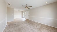 Located at 2100 S Conway Rd in Orlando, FL, this one-bedroom, one-bathroom unit offers a practical and well-organized single-floor layout. The open-concept living and kitchen area serves as the heart of the home, where light wood-look flooring runs throughout. The kitchen features a pass-through counter with granite-look laminate surfaces, white cabinetry, a black refrigerator, and a sink with a tiled backsplash — all visible from the living area, creating a connected and functional space. The living room is finished with plush carpet, a ceiling fan with integrated lighting, and a sliding glass door that leads to an outdoor area, allowing natural light to flow in. A hallway connects the main living space to the bedroom and bathroom. The bedroom is a comfortable, carpeted room equipped with a ceiling fan and double windows that offer pleasant views of a pool and lush outdoor greenery. The bathroom includes a full soaking tub and shower combination with clean white tile surround, a toilet, and wood-look flooring. Throughout the unit, a neutral warm-beige color palette, textured ceilings, and white trim create a clean, cohesive aesthetic.