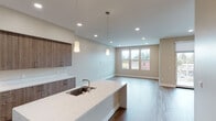 This single-floor residence showcases a thoughtfully designed open-concept layout with modern finishes throughout. The kitchen serves as a central highlight, featuring a large island with a white quartz countertop, an undermount sink, and stylish pendant lighting overhead. Wood-toned cabinetry extends floor to ceiling, complemented by stainless steel appliances including a gas range with a wall-mounted hood, a French door refrigerator, and ample storage. The kitchen flows seamlessly into a spacious living area illuminated by recessed lighting and a large window that brings in natural light and outdoor views.

Wide-plank wood flooring runs throughout the main living spaces and bedrooms, adding warmth and continuity. The bedrooms are generously sized with neutral tones, recessed lighting, and windows fitted with roller shades. One bedroom includes a closet with built-in shelving.

The bathrooms are finished with light tile flooring and warm wood vanities topped with white quartz countertops. One bathroom features a dual-sink vanity, a glass-enclosed walk-in shower, and a separate soaking tub. A clean, well-lit hallway with crisp white trim and panel doors connects the various rooms, contributing to the unit's cohesive and contemporary aesthetic.